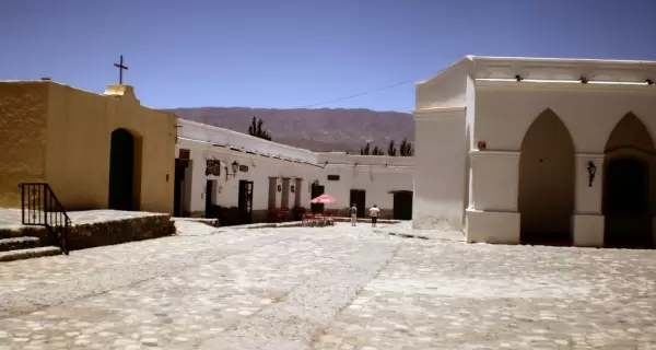 Casas coloniales y la iglesia de Cachi sobresaliendo frente al Nevado de Cachi en un cielo azul profundo.